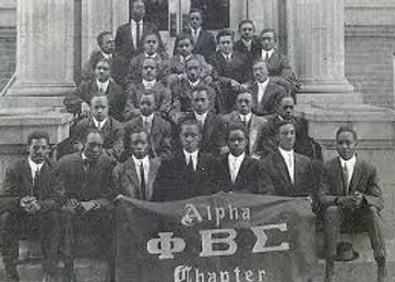 Early members of Phi Beta Sigma posed on steps with an Alpha Chapter banner