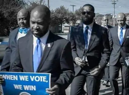 Brothers marching with a sign reading When We Vote We Win